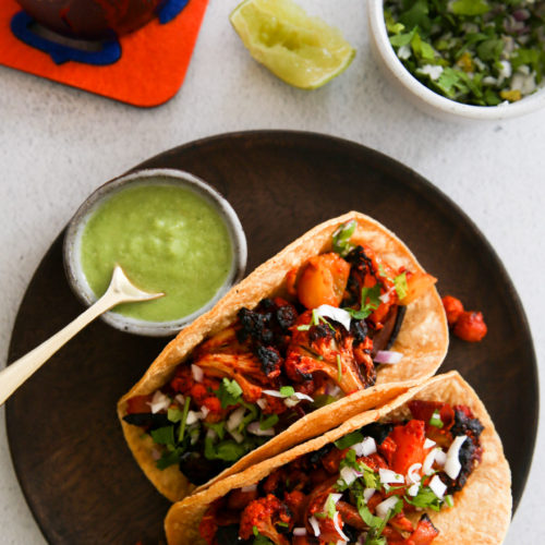 Dos tacos en un plato junto a un plato de guacamole.