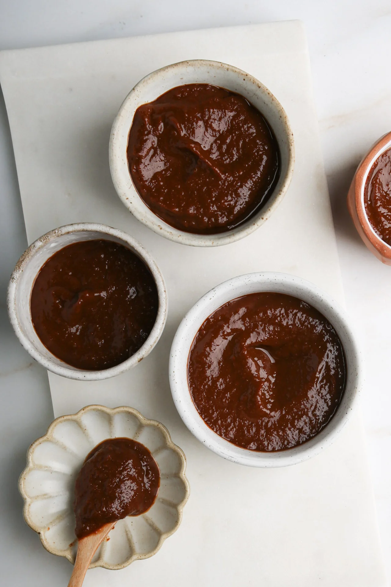 Tazones peque&ntilde;os con chamoy de jamaica casero de color morado intenso sobre una superficie de m&aacute;rmol