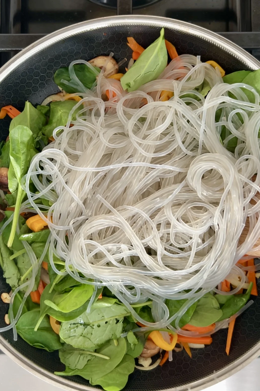 Fideos de cristal remojados agregados sobre las verduras salteadas en un sart&eacute;n